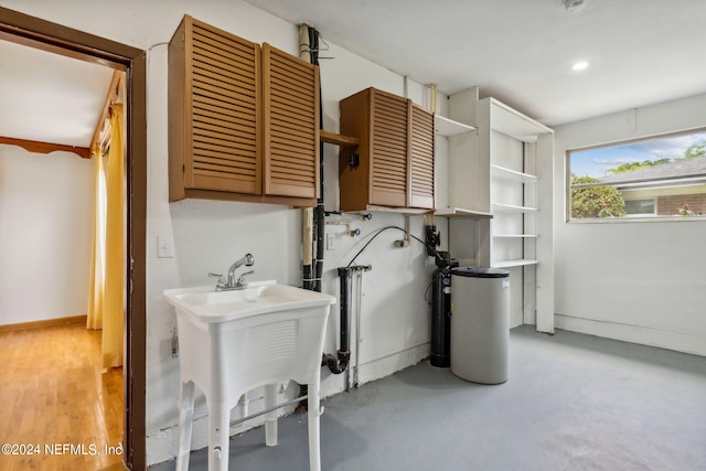 clothes washing area with cabinets and sink