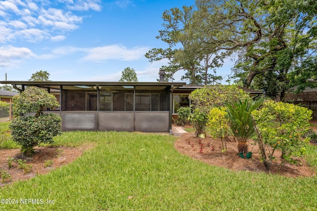 rear view of house featuring a sunroom and a yard