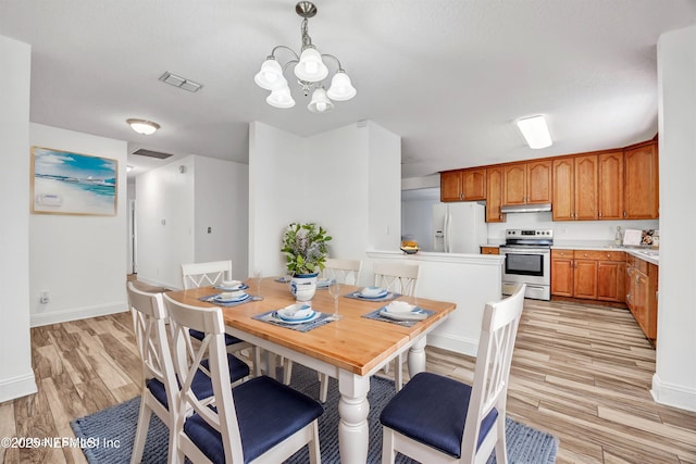 dining space with light hardwood / wood-style flooring and a notable chandelier