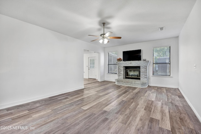 unfurnished living room with ceiling fan, a fireplace, and light hardwood / wood-style floors