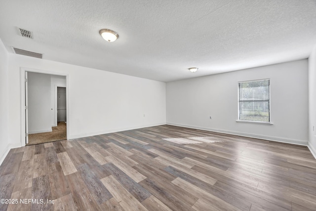 empty room with a textured ceiling and hardwood / wood-style flooring