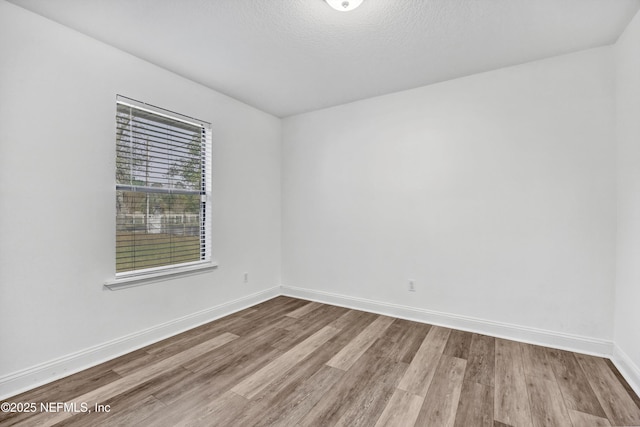 empty room with hardwood / wood-style floors and a textured ceiling