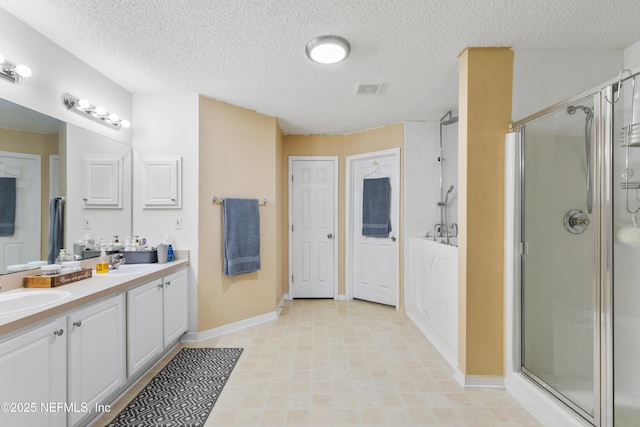 bathroom featuring vanity, a shower with shower door, and a textured ceiling