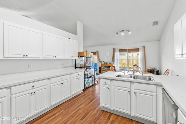 kitchen featuring dishwasher, white cabinets, sink, light hardwood / wood-style floors, and kitchen peninsula