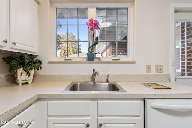 kitchen featuring sink, white dishwasher, and white cabinetry