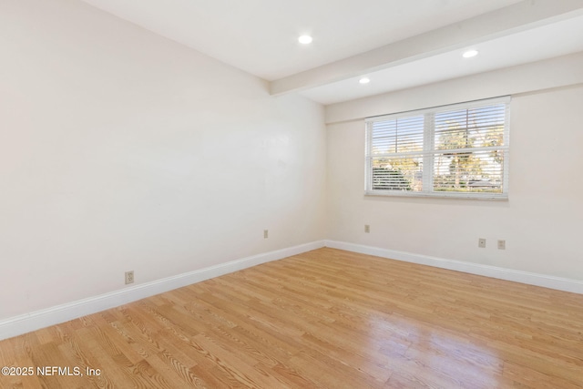 unfurnished room with light wood-type flooring and beamed ceiling