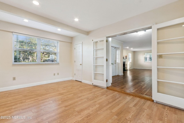 spare room featuring beamed ceiling and light hardwood / wood-style floors