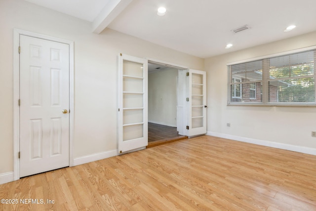 unfurnished bedroom featuring light hardwood / wood-style flooring and beam ceiling