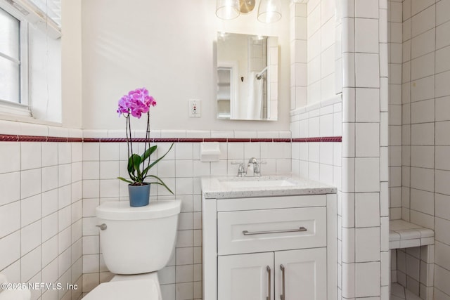 bathroom featuring vanity, tile walls, and toilet