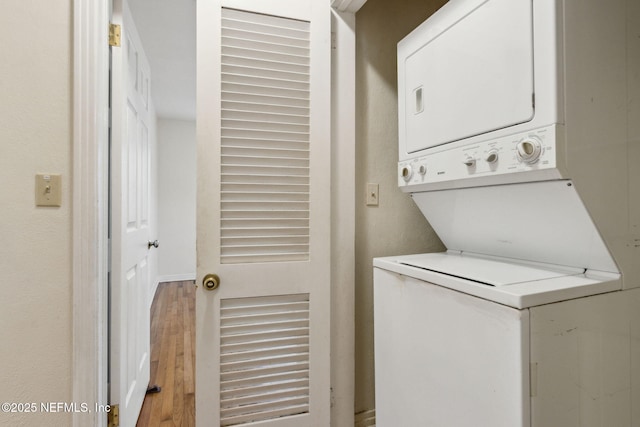 laundry room featuring stacked washer and dryer and hardwood / wood-style floors