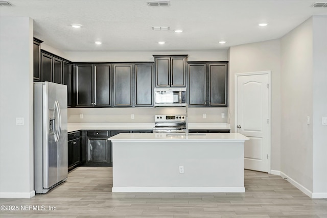 kitchen with a kitchen island with sink, sink, light hardwood / wood-style floors, and appliances with stainless steel finishes