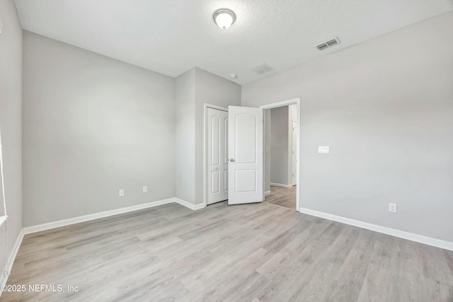 unfurnished bedroom with a textured ceiling, a closet, and light wood-type flooring