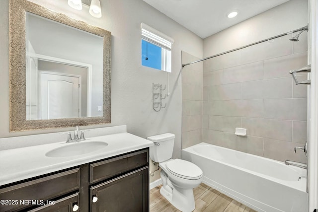 full bathroom featuring tiled shower / bath, hardwood / wood-style floors, vanity, and toilet