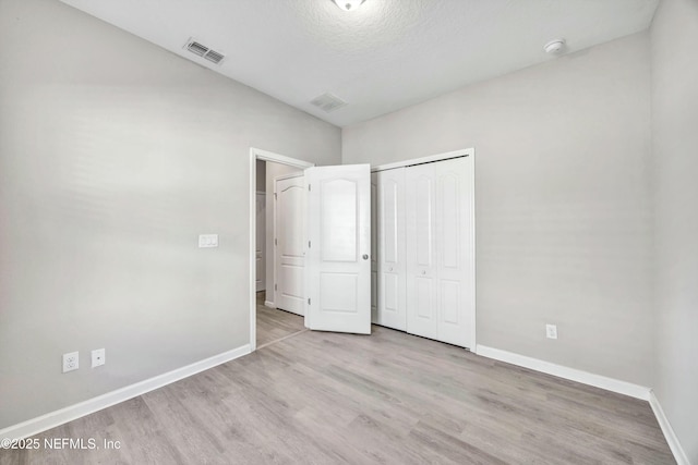 unfurnished bedroom with a closet and light wood-type flooring