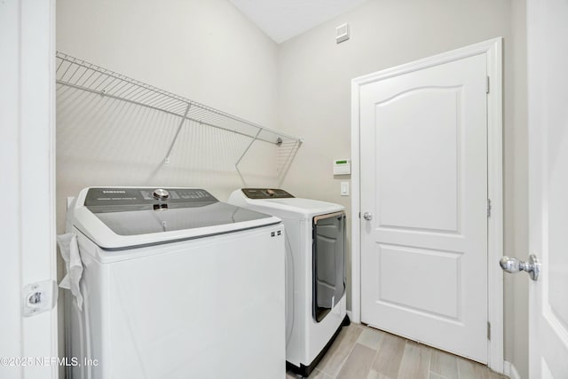 laundry room with light wood-type flooring and washer and clothes dryer