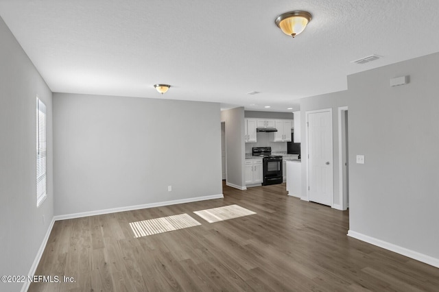 unfurnished living room with a textured ceiling and dark wood-type flooring