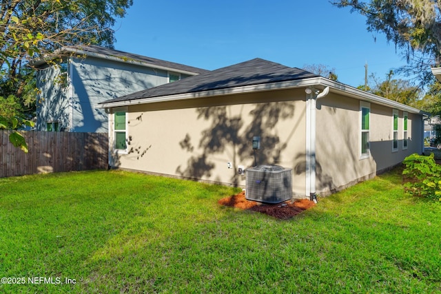 back of property with central air condition unit and a yard