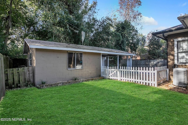 rear view of house featuring a lawn and central air condition unit