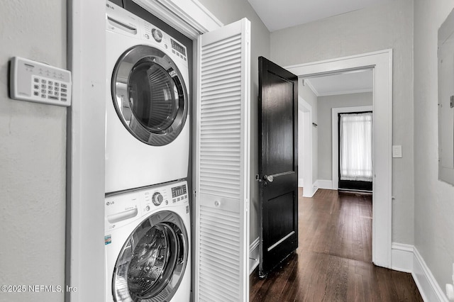 laundry room with dark hardwood / wood-style flooring, ornamental molding, and stacked washer and dryer