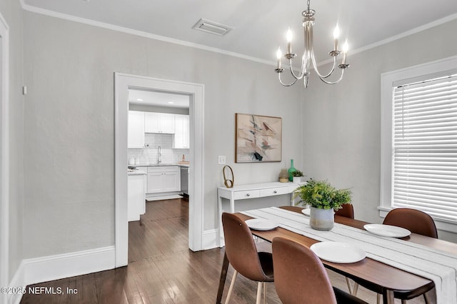 dining room featuring crown molding, sink, dark wood-type flooring, and a notable chandelier