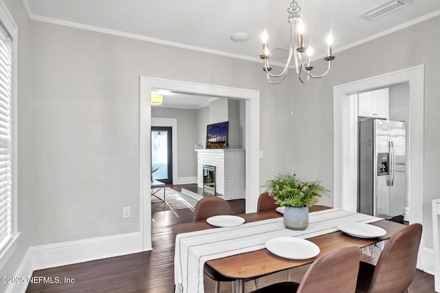 dining space with a fireplace, dark hardwood / wood-style flooring, an inviting chandelier, and crown molding