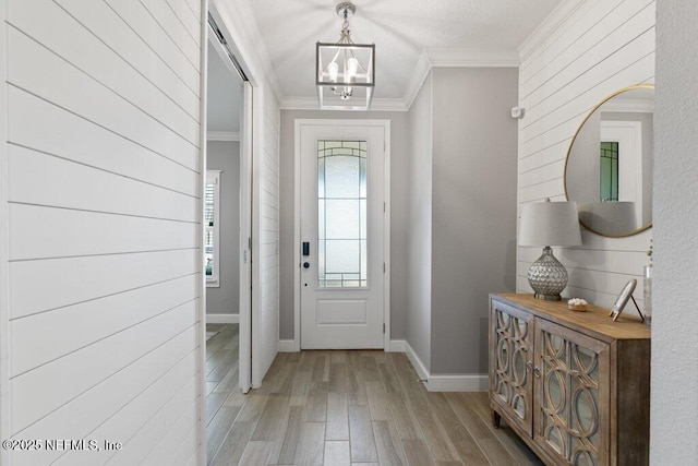 entryway with a notable chandelier, light wood-type flooring, crown molding, and wooden walls