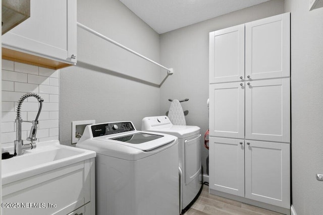 laundry area featuring cabinets, independent washer and dryer, light hardwood / wood-style flooring, and sink