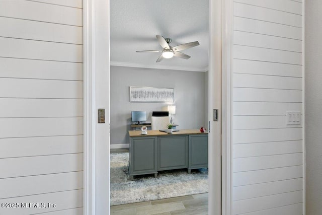 home office featuring hardwood / wood-style floors, wooden walls, ceiling fan, and ornamental molding