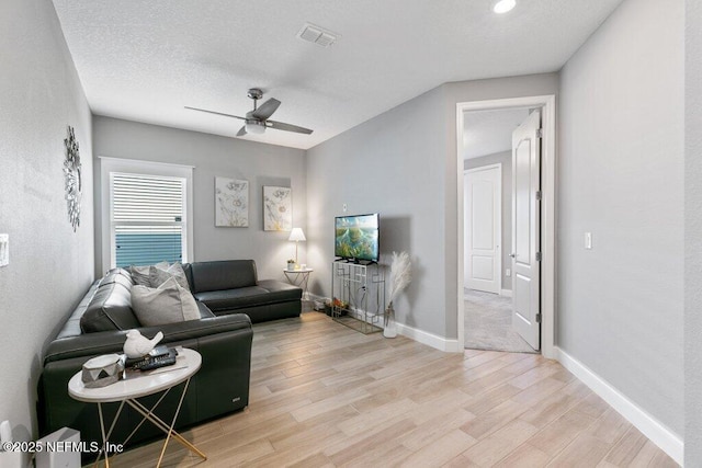 living room with ceiling fan, light hardwood / wood-style floors, and a textured ceiling