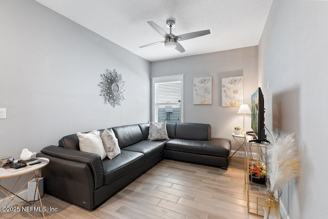 living room with ceiling fan, light hardwood / wood-style floors, and a textured ceiling