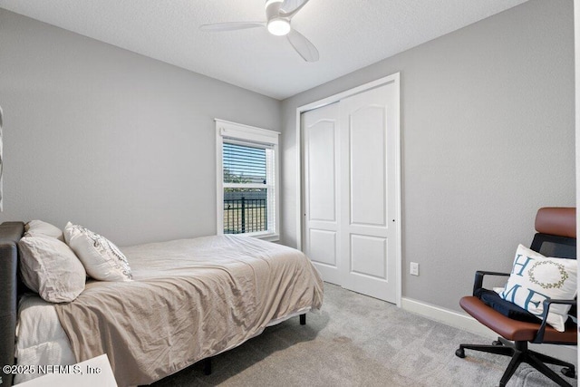 bedroom with ceiling fan, light carpet, and a closet