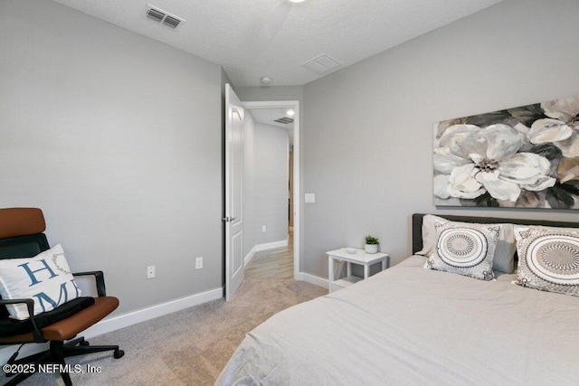 bedroom with a textured ceiling, ceiling fan, and light carpet