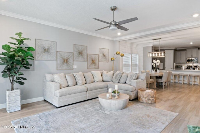 living room featuring crown molding, ceiling fan, and light wood-type flooring