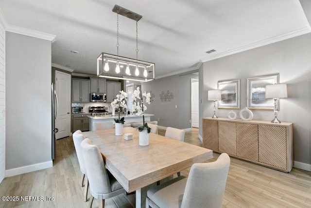 dining room with light wood-type flooring and crown molding