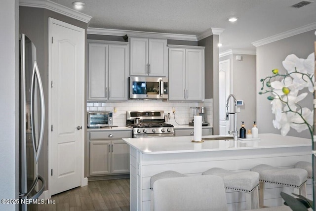 kitchen featuring a kitchen bar, appliances with stainless steel finishes, ornamental molding, and sink