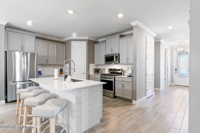 kitchen featuring a kitchen breakfast bar, gray cabinets, and stainless steel appliances