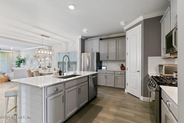 kitchen with decorative backsplash, sink, an island with sink, and appliances with stainless steel finishes