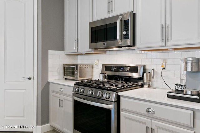 kitchen with white cabinets, appliances with stainless steel finishes, and decorative backsplash