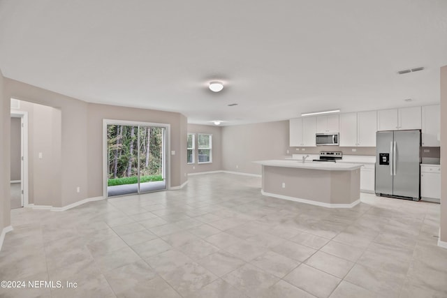 kitchen featuring white cabinets, an island with sink, light tile patterned floors, and appliances with stainless steel finishes