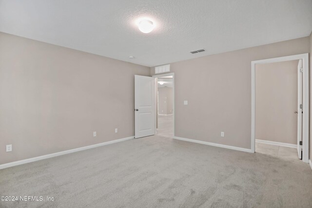 carpeted empty room featuring a textured ceiling