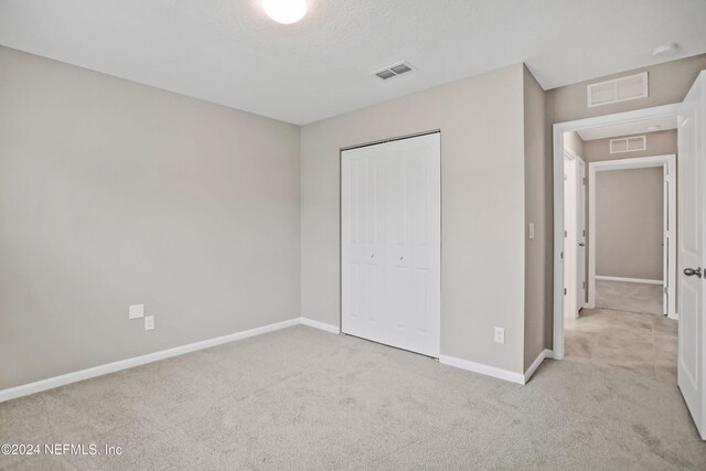 unfurnished bedroom featuring light colored carpet and a closet