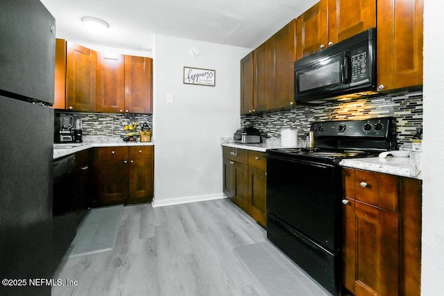 kitchen with black appliances, decorative backsplash, light hardwood / wood-style floors, and light stone countertops