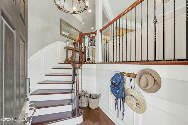 stairway with wood-type flooring and an inviting chandelier