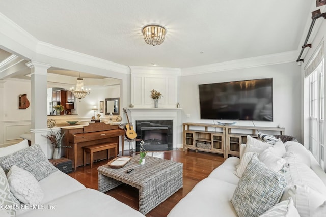 living room with a large fireplace, dark hardwood / wood-style flooring, ornamental molding, and a chandelier