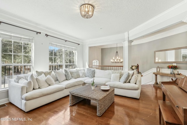 living room featuring a textured ceiling, an inviting chandelier, crown molding, and wood-type flooring