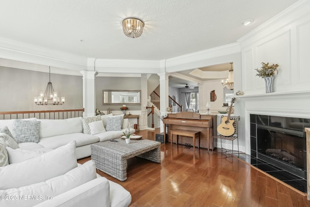 living room featuring a textured ceiling, dark wood-type flooring, ceiling fan with notable chandelier, and a tiled fireplace