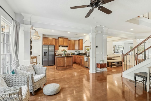 kitchen with stainless steel appliances, light hardwood / wood-style floors, plenty of natural light, ceiling fan, and decorative columns