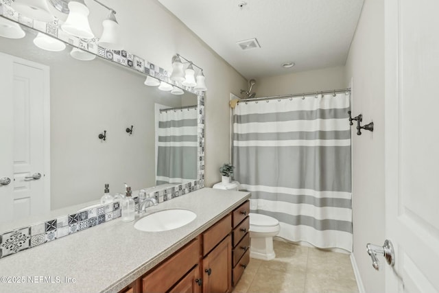 bathroom with toilet, vanity, and tile patterned flooring