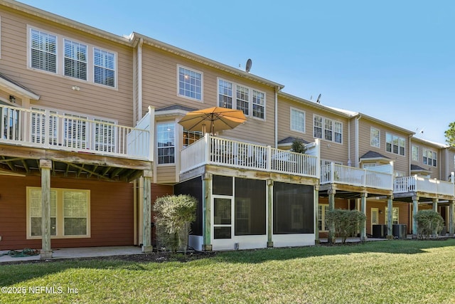 rear view of house featuring central AC unit, a yard, and a sunroom