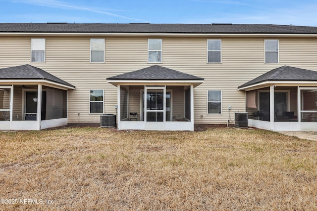 rear view of house featuring cooling unit, a sunroom, and a lawn